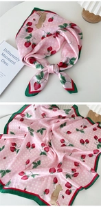 Détail d'un foulard carré soyeux avec imprimé fraises et chiots en rose et vert tendre