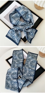 Detail of a narrow silk scarf with blue and white floral patterns tied in a bow
