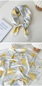 Détail d'un foulard en soie avec motif floral de marguerites jaunes et feuilles vertes