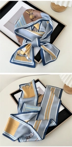 Detail of long silk scarf with horse print and stripes, elegant grey-blue and yellow tones