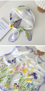 Détails d'un foulard en soie blanc nacré avec motifs floraux violets et papillons