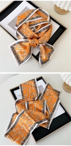 Detail of thin orange silk scarf with vintage abstract patterns and retro contrast borders