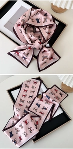Detailed view of pink silk twilly scarf with horse patterns and dark brown edges
