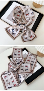 Detail view of a slim silk scarf with equestrian horse prints and brown border