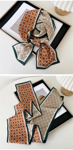 Detail of dual-sided floral skinny scarf with orange patterns and dark green borders