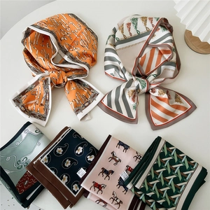 Flat lay of assorted printed skinny silk scarves with elegant patterns on a white table