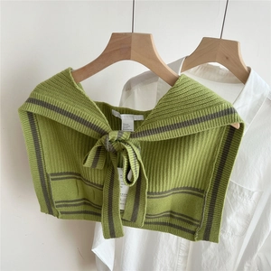 Detail of green striped knitted shawl wrap with bow tie on a white shirt