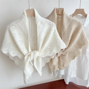 Close-up of hollow knit shawls in beige and apricot featuring crochet diamond patterns