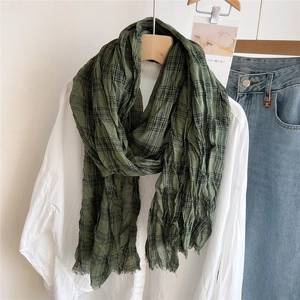 Detail of green and black plaid cotton scarf with natural wrinkles and frayed edges