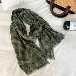 Detail of dark green checkered linen scarf with fringe edges and pleated texture