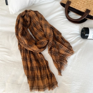 Close-up of caramel brown checkered cotton linen scarf with frayed edges and crinkle texture