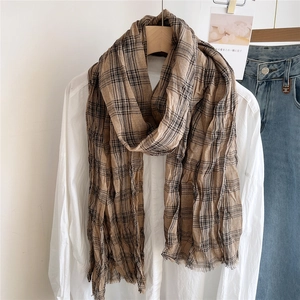 Detail of a brown and black plaid cotton linen scarf with soft pleats and frayed edges