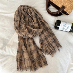 Detail of earthy brown plaid cotton linen scarf with fine tassel edges and soft texture