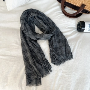 Detailed view of grey checkered linen scarf with natural frayed edges on a white backdrop