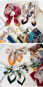 Detail view of assorted floral silk scarves and hair bands on a white minimalist table