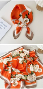 Detail of vibrant orange floral silk scarf with vintage belt pattern and smooth texture
