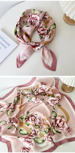 Close-up of pink silk scarf with red roses, gold chains, and leather strap patterns