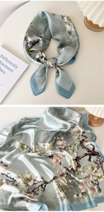 Close-up of mint blue silk scarf with white magnolia floral print and fine hemmed edges