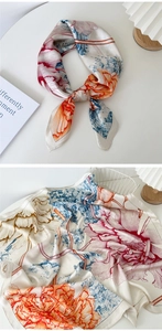 Silk floral scarf with pink and orange flower patterns displayed on a white table