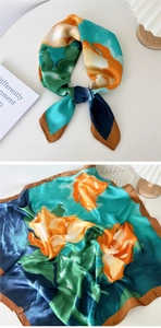 Detailed pattern of floral silk scarf with orange blooms and navy blue artistic borders