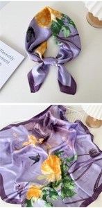 Detail of silk scarf showing lavender floral pattern and smooth satin texture on white table