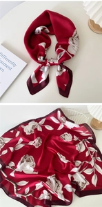 Detail view of a burgundy square silk scarf featuring realistic white rose floral patterns