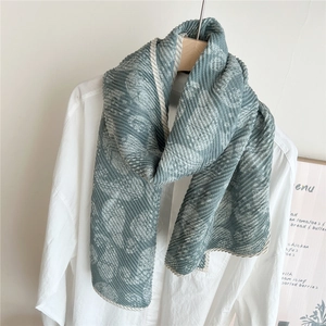 Détail d'une écharpe longue à motif paisley bleu avec plis verticaux sur chemise