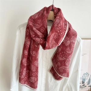 Détail d'une écharpe plissée rouge à motif paisley sur une chemise blanche