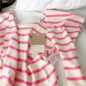 Dettaglio dello scialle in maglia a righe rosa con etichetta materiale e marchio
