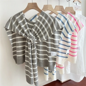 Scialle in maglia a righe da donna in grigio, blu e rosa su appendini in legno naturale