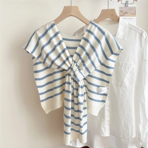 Dettaglio dello scialle in maglia a righe blu e bianche annodato su camicia