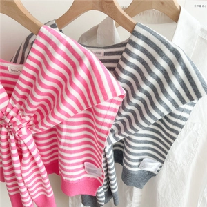 Detailed view of pink and grey striped knitted shawls paired with white shirts