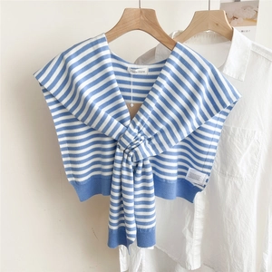 Detail of blue and white striped knitted shawl draped over a white shirt on a hanger