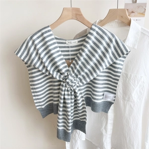 Detailed close-up of grey and white striped knitted shawl with logo label on white shirt