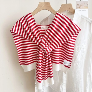 Detail shot of a red and white striped knitted shawl wrap on a wooden hanger