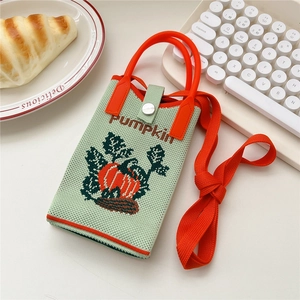 Detail der grünen gestrickten Handytasche mit Kürbismotiv und orangefarbenem Gurt