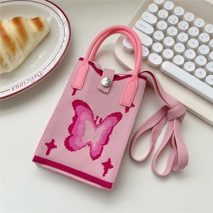 Detailansicht der rosa gestrickten Handytasche mit Schmetterlingsmuster und Gurt auf Tisch