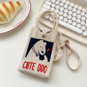 Detail der beigen Strick-Handytasche mit blauem Hundemuster und Druckknopfverschluss