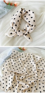 Gros plan d'un foulard en lin et coton crème à pois noirs avec une texture douce