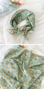 Détail d'un foulard en coton et lin vert clair avec imprimé floral et bordures roulées fines