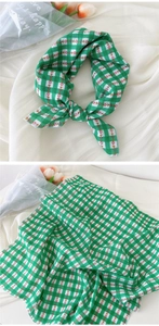 Détail d'un foulard à carreaux verts et blancs avec broderie florale sur tissu doux