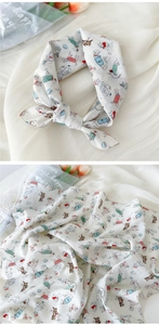 Détail d'un foulard en coton et lin beige avec des motifs de chiens colorés et bordure fine