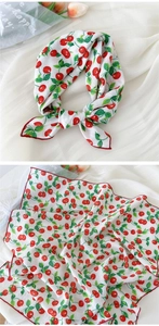 Détail d'un foulard blanc avec motifs cerises rouges et bords surjetés