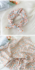 Détail d'un foulard en coton blanc avec imprimés de fraises oranges et motifs de feuilles