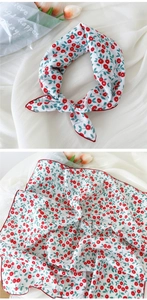 Détail d'un foulard blanc en coton et lin avec imprimé cerise et bordure rouge