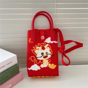 Détail du sac dragon tricoté rouge avec bouton cœur et texture de poignée tissée