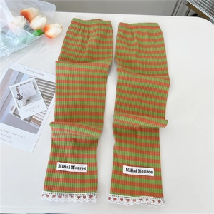 Detail of green and orange striped arm sleeves with white lace trim and brand label