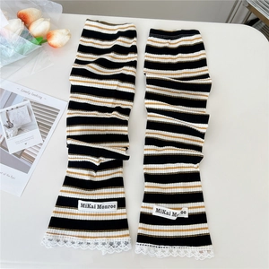 Macro detail of tricolor striped knit arm sleeves with white lace trim and brand label