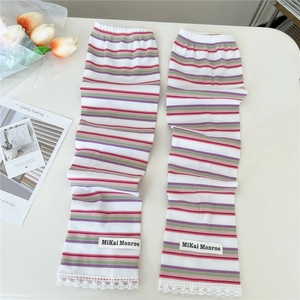 Close-up of colorful striped knitted leg warmers with delicate white lace trim and logo