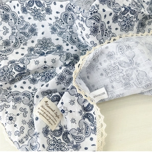 Dettaglio di una sciarpa in viscosa con stampa paisley, pizzo beige ed etichetta stile